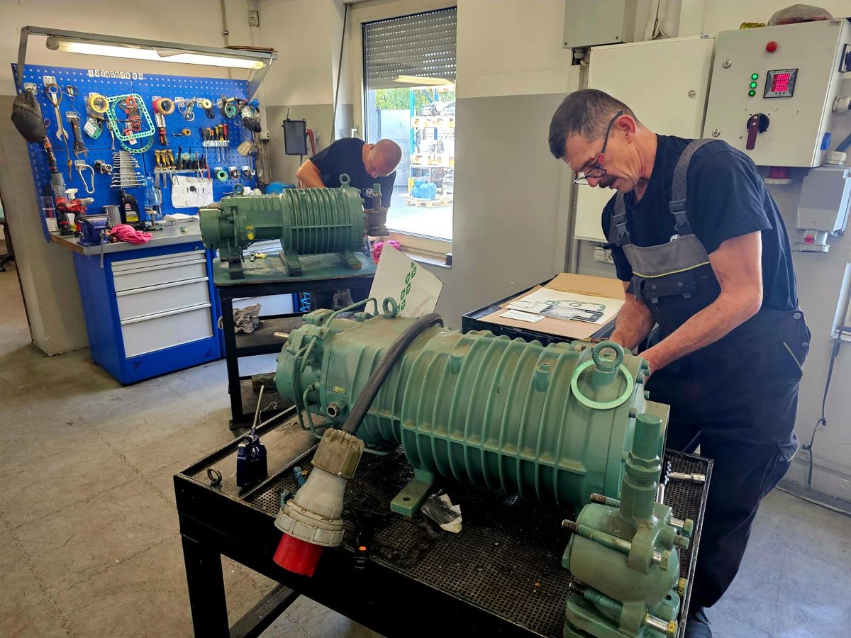 Technik Compressland przy naprawie sprężarki śrubowej na stanowisku warsztatowym