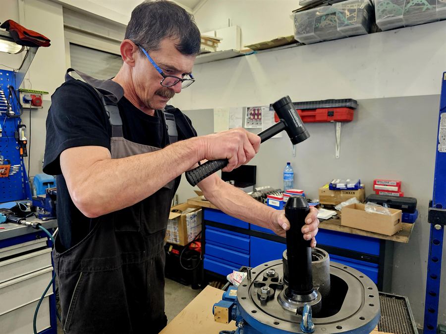 Technik Compressland naprawiający sprężarkę chłodniczą na stanowisku warsztatowym